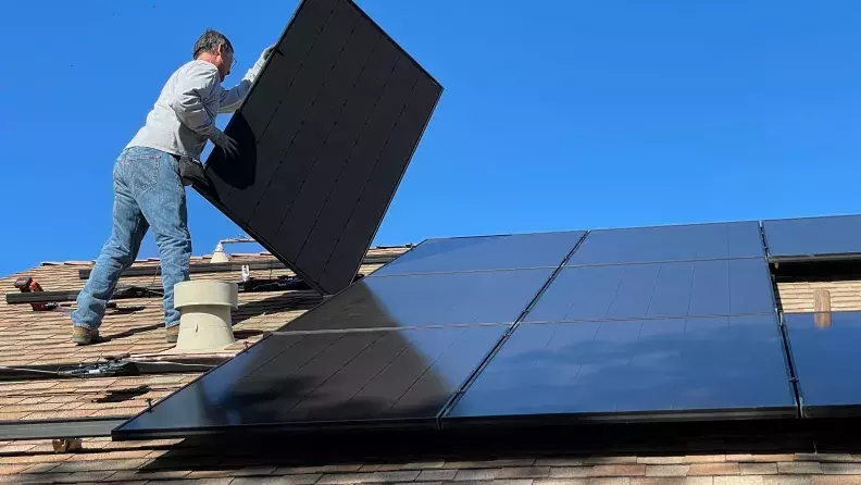 Worker installing solar panels on a roof